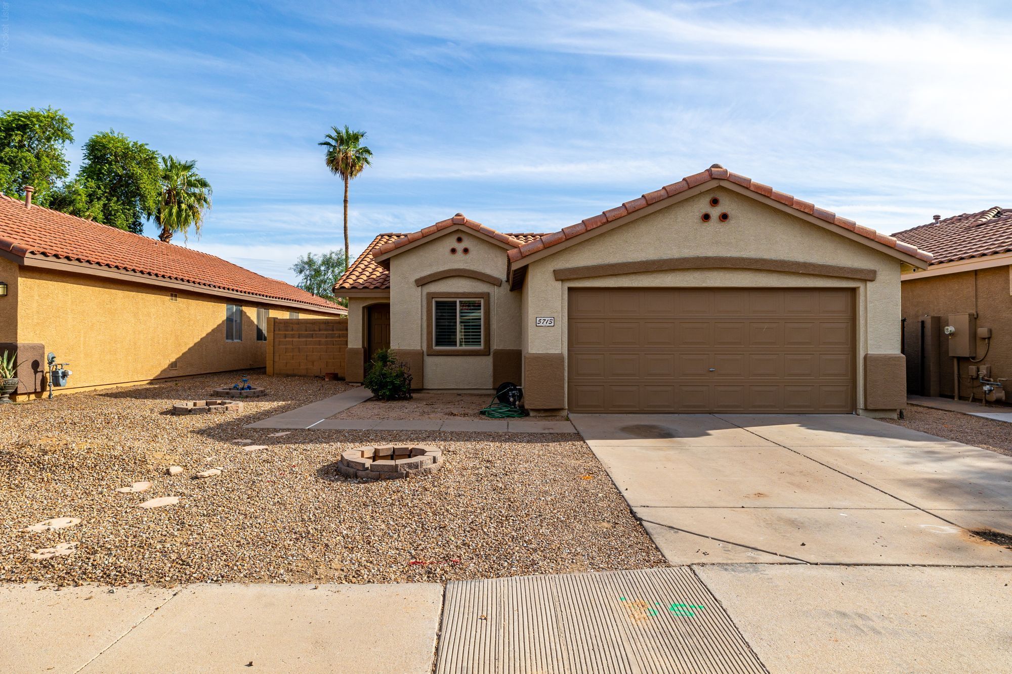 Single-story home with a two-car garage, tile roof, and desert landscaping