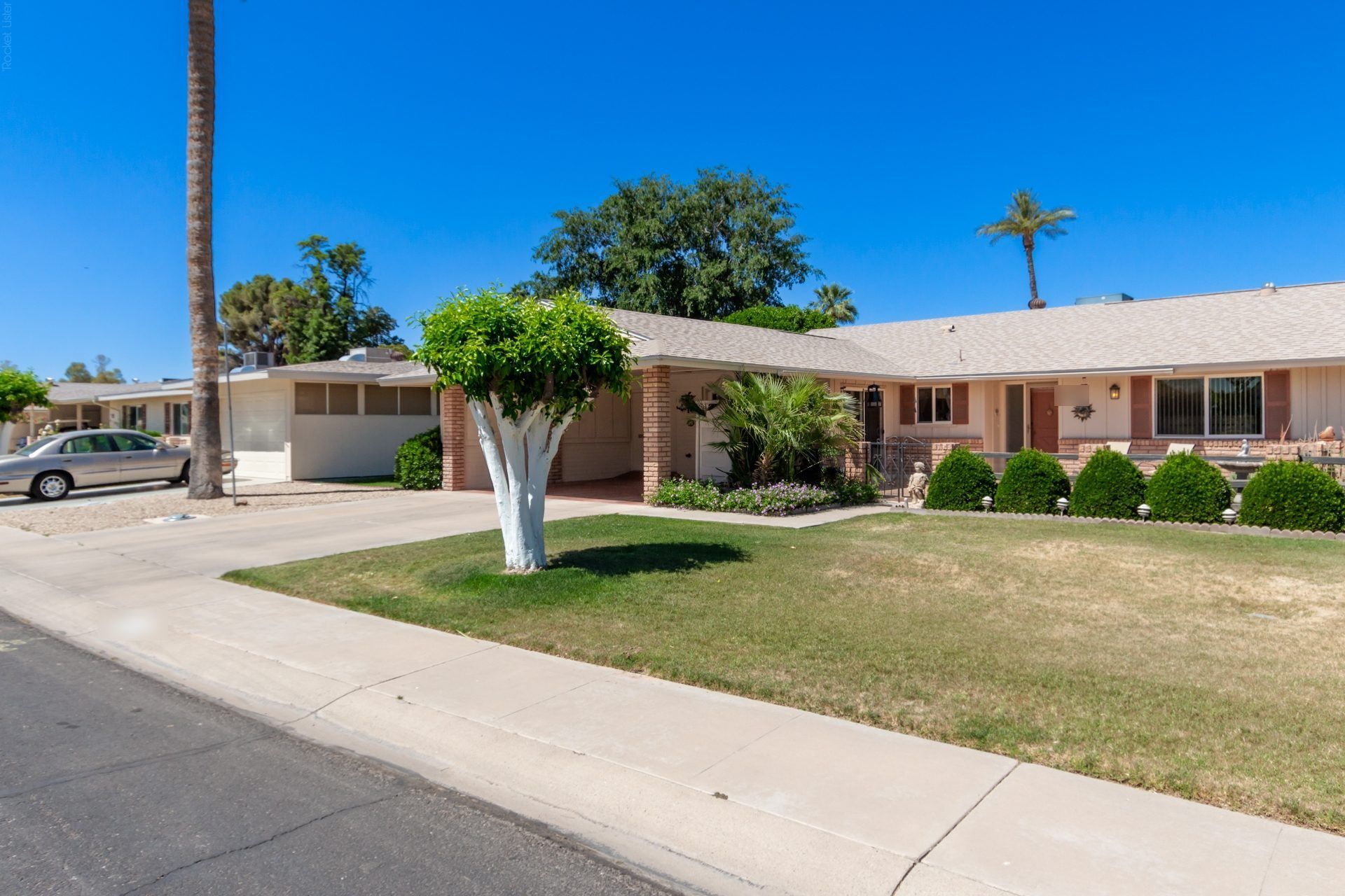 Single-story ranch home with a green lawn and mature trees